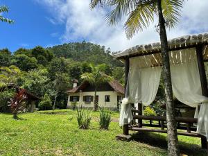 uma casa com um banco em frente a um quintal em Casa Chalé Chácara Caminho do Vale em Nova Friburgo