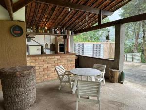 un patio con tavolo, sedie e bancone di Chalé Chácara Caminho do Vale CASA DE TEMPORADA a Nova Friburgo