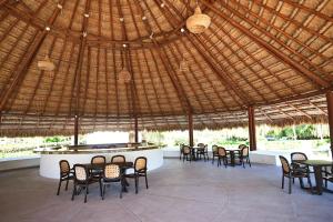 a restaurant with tables and chairs under a straw roof at Beachfront apartment Blue Vista in Cancún