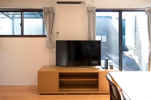 a flat screen tv sitting on top of a wooden cabinet at 一棟貸しnuevoL7～暮らすように泊まる北群馬の冒険はここから in Numata