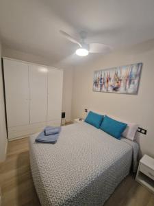 ein Schlafzimmer mit einem Bett mit blauen Kissen in der Unterkunft Apartamento Caribe Playa in Calpe