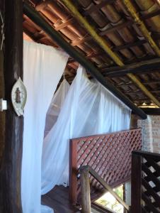 1 dormitorio con cortinas blancas y banco en Villa Sowilo, en Trancoso