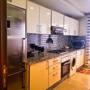 uma cozinha com armários brancos e um frigorífico de aço inoxidável em Appartement Résidence avec piscine intérieure et Piscine couverte em Marrakech