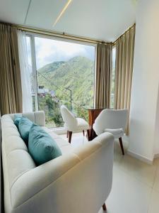 uma sala de estar com um sofá branco e uma grande janela em Hostal Balcon del Cielo em Baños