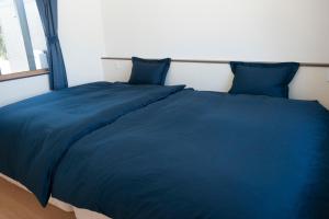 a blue bed with blue pillows in a bedroom at 一棟貸しnuevoL7～暮らすように泊まる北群馬の冒険はここから in Numata