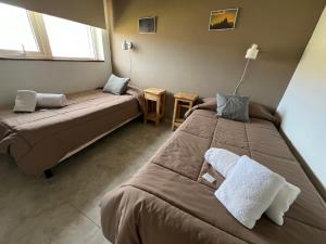 1 dormitorio con 2 camas, mesa y ventana en Buenavista Chalten, Casa de Montaña en El Chaltén