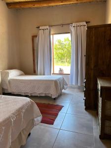 1 dormitorio con 2 camas y ventana en Tierra Primitiva en Tilcara