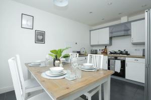 a kitchen with a wooden table and white cabinets at Cosy Home in Canterbury Free Parking for 2 cars in Chartham