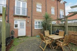 a patio with a wooden table and chairs in front of a brick building at Serene Escape, Perfect Location in Canterbury Free Parking in Chartham