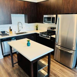 a kitchen with a table and a stainless steel refrigerator at Luxury Condo with Pool & Gym ! in Glendale