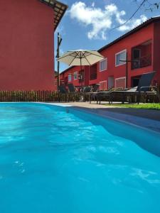 a large swimming pool in front of a red building at Linda Casa de Veraneio em Monte Gordo/Ba in Camacari