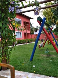 un niño está jugando en un columpio en un patio en Linda Casa de Veraneio em Monte Gordo/Ba, en Camassari