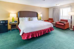 a bedroom with a large bed and a red chair at Alliance Hotel and Suites in Alliance