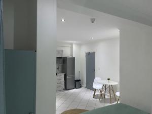 eine weiße Küche mit einem Tisch und einem Kühlschrank in der Unterkunft Cavendish Suite Bachelor in Kapstadt
