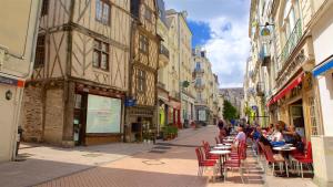 uma rua da cidade com mesas, cadeiras e edifícios em Charme Citadin Angevin - hyper centre Angers em Angers