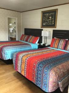 two beds with colorful blankets and pillows in a room at Starlight Motel in Big Pine