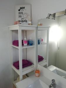 a bathroom with a sink and a shelf with purple towels at Carmencita y Manolito in Telde