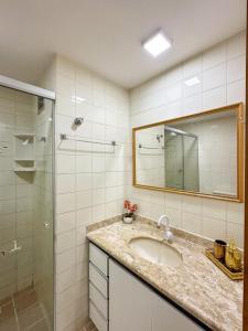 y baño con lavabo, ducha y espejo. en Apartamento com Vista para o Mar en Guarapari