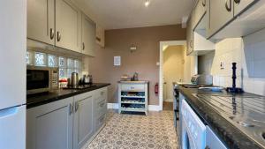 a kitchen with white cabinets and black counter tops at Luxury 4 Bedroom Seaside Apartment - Glan Y Werydd House in Barmouth