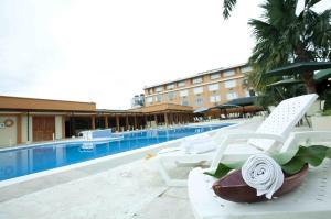 une piscine avec des chaises longues blanches à côté d'un hôtel dans l'établissement Hotel Anaconda, à Leticia