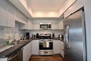 cocina con armarios blancos y nevera de acero inoxidable en Los Angeles Premium 2BR&2BT Suites with Free Parking, en Los Ángeles