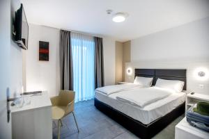 Miralago Locarno Easy Rooms في لوكارنو: غرفة نوم بسرير ومكتب وتلفزيون