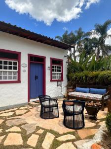 蒂拉登蒂斯的住宿－Chafariz Por Um Triz，房屋前设有带椅子和长凳的庭院