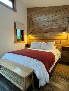 - une chambre avec un grand lit et un mur en bois dans l'établissement Cabañas Boutique con Tinaja Privada en Pucón, à Pucón