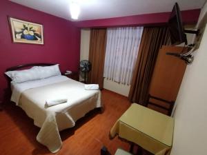 1 dormitorio con cama blanca y paredes moradas en Hospedaje Concordia, en Chiclayo