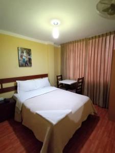 Un dormitorio con una gran cama blanca y una mesa en Hospedaje Concordia en Chiclayo