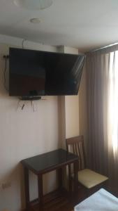 Habitación con mesa y TV en la pared. en Hospedaje Concordia en Chiclayo