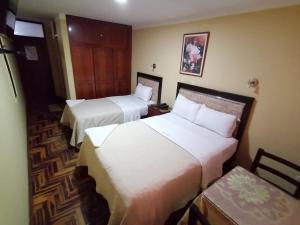 um quarto de hotel com duas camas e uma cadeira em Hospedaje Concordia em Chiclayo
