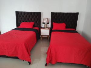 a bedroom with two beds with red sheets and a night stand at Casa Maikai Tarapoto in Tarapoto