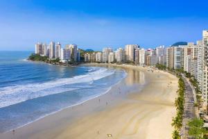 a view of a beach with buildings and the ocean at sobrado 08 com duas suítes, conf in Guarujá