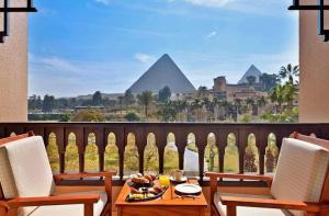a table with a bowl of fruit on a balcony with the pyramids at Just A Break - جست بريك لحجز الفنادق in Cairo