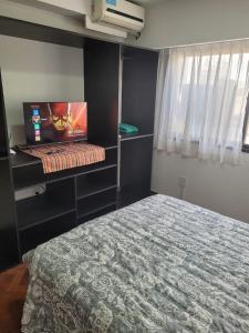 ein Schlafzimmer mit einem Bett und einem Laptop auf einem Regal in der Unterkunft Dpto España ubicadísimo!!! in Mendoza