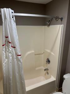 La salle de bains est pourvue d'un rideau de douche, d'une baignoire et de toilettes. dans l'établissement Red Roof Inn Flint, à Flint