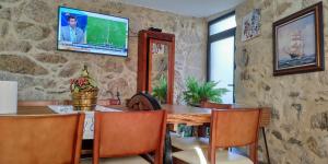 a dining room with a table and a tv on a stone wall at Quinta da Eira in Sever do Vouga