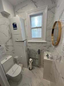 a white bathroom with a toilet and a window at Cambridge Central Rooms - Tas Accommodations in Cambridge