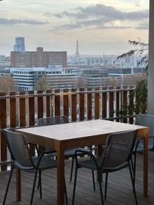 einen Tisch und Stühle auf einem Balkon mit Stadtblick in der Unterkunft SKY - ASNIERES in Asnières-sur-Seine