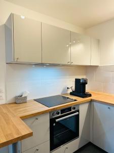 a kitchen with white cabinets and a stove top oven at SKY - ASNIERES in Asnières-sur-Seine