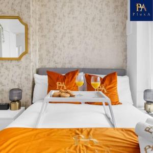 a bed with orange pillows and a tray with two glasses at 3 Bed by Birmingham Airport in Birmingham