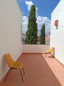 two chairs on a balcony with a view of a tree at Hermoso departamento amueblado en Aguascalientes. Céntrico in Aguascalientes