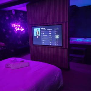 a bedroom with a bed and a tv with purple lights at L'Escale Suite & Spa in Therdonne +11 photos