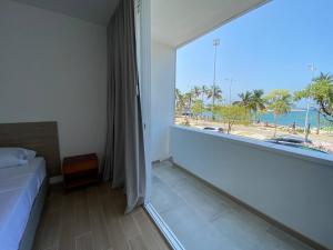 a bedroom with a large window with a view of the beach at Panamerican Hostel in Santa Marta