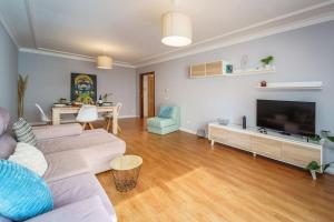 a living room with a couch and a tv at Lovely&Cozy apartment in Lagoa