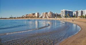 a beach with buildings and people walking on the beach at UIM Mediterraneo Cendoya 2 Wifi in Puerto de Sagunto