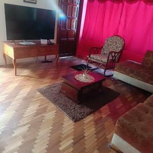 Agradable minidepartamento central en Ambato, para una a seis personas في أمباتو: غرفة معيشة مع تلفزيون وأريكة وطاولة