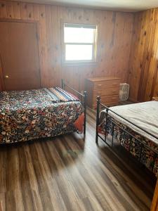 a bedroom with two beds and a window and wooden walls at South Fork Lodge & RV Park Colorado in South Fork
