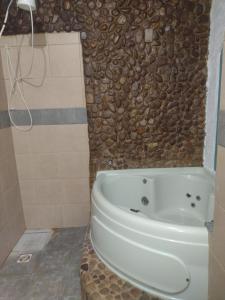 y baño con bañera y pared de piedra. en Cada De Hospedagem Vida No Paraíso en Angra dos Reis